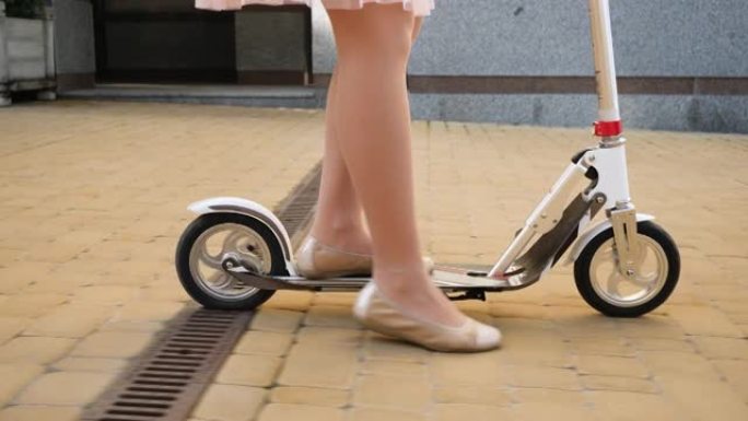 在城市街道上站立和骑在踏板车上的芭蕾舞平底鞋中跟随女性脚的特写4k视频