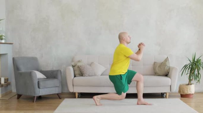 一个年轻人在家靠着灰色的墙锻炼。侧视图。