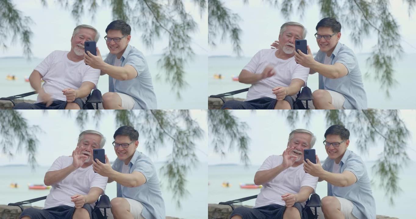 亚洲老人和儿子暑假去海边旅行。年轻人通过视频通话与家人交谈社交媒体概念技术