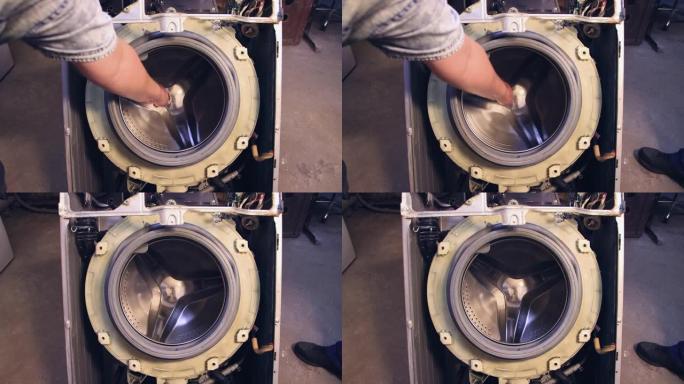一个人的手转动洗衣机的滚筒和洗衣机。
