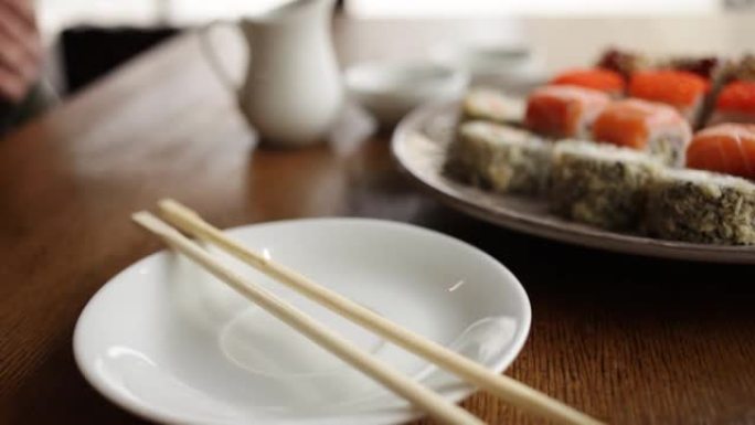 咖啡馆餐厅里的日本寿司卷。酱油、木棍、山葵、生姜。一张桌子，一扇俯瞰城市的窗户。晚餐，早餐，午餐。一