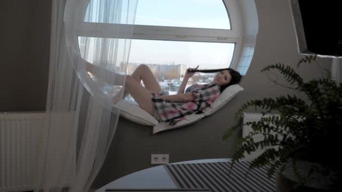 一个年轻女子坐在窗台上在家放松