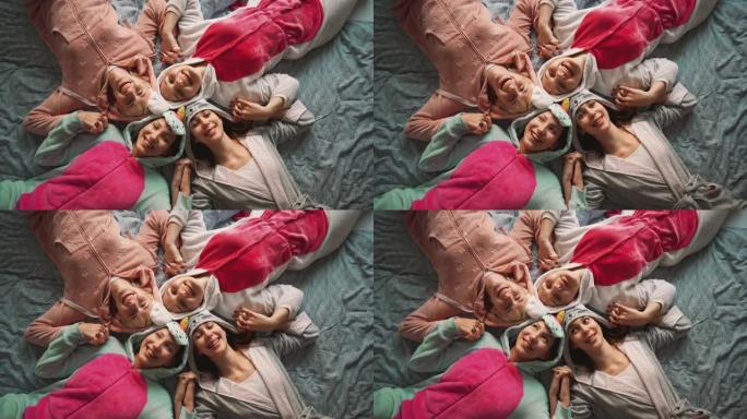 四个穿着睡衣的女友躺在床上微笑的俯视图