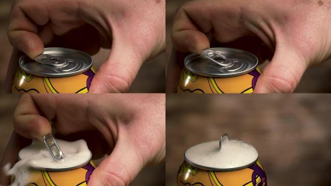男人的手打开一罐摇晃的啤酒，一杯泡沫的冷饮从里面倒出来。一个男人的手在模糊的背景下打开搅拌啤酒罐的详