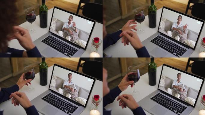 混合种族男子坐在桌子旁，使用笔记本电脑与男性朋友进行视频通话