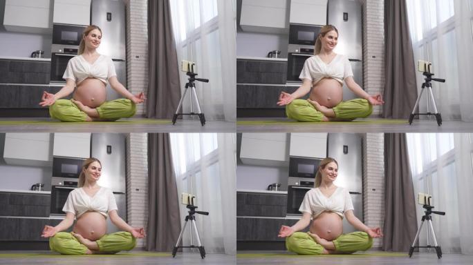 孕妇在家用智能手机做瑜伽。准妈妈进行产前视频培训。一名妇女在怀孕期间冥想