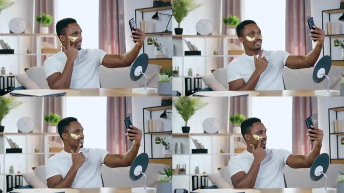 英俊的微笑满足的非洲裔美国人看着手机摄像头，看着他的倒影，用水凝胶眼罩，面部护理概念
