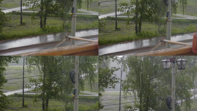 外面下着大雨。从窗户可以看到树木，道路和杆子。通常的城市景观