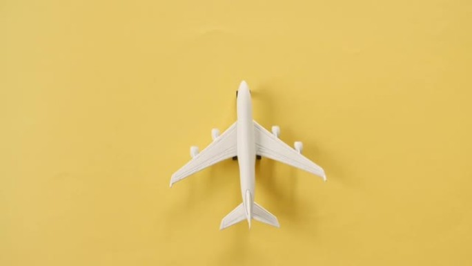 白色和黄色背景上的棕榈叶玩具飞机的模型。客机飞行，移动。航空运输、旅游、度假、旅行的概念。顶视图