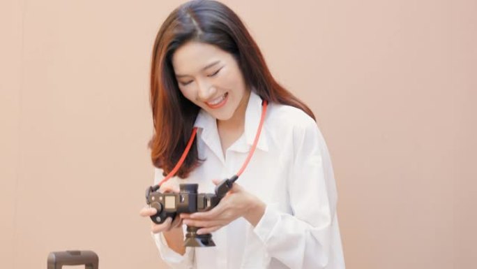 美丽的亚洲女孩在相机上预览她是一名旅行摄影师和互联网旅行建议的博客作者。她在网上赚钱。