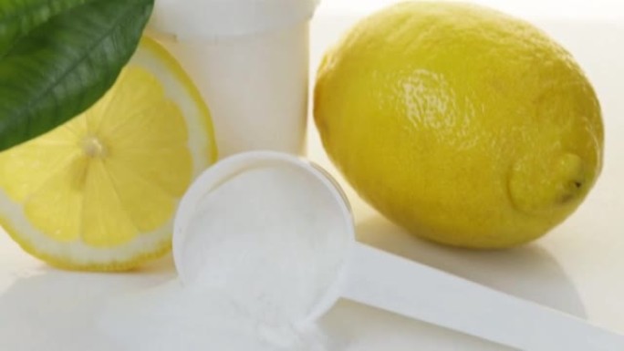 维他命C粉。罐子和量匙，维生素c白色粉末和柠檬切成轻背景。预防感冒和流感。增强免疫力。