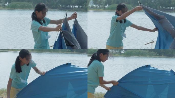亚洲女孩试图在户外湖附近的地面上搭帐篷，生活方式概念。