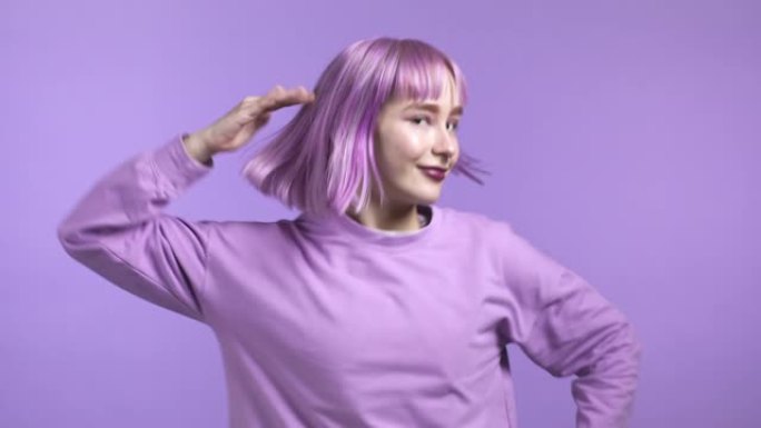 紫色发型迷人的女人在紫罗兰工作室背景上跳舞。心情积极的女孩zoomer。