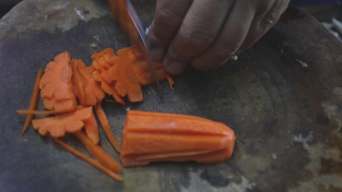 用小刀在木砧板上手切胡萝卜。