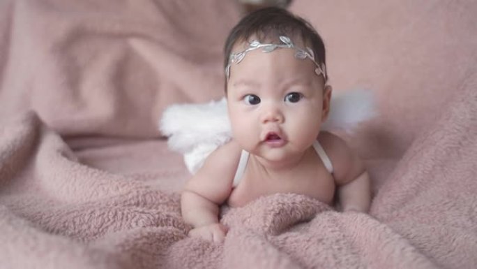 3个月亚洲婴儿婴儿在丘比特天使之翼爬行软毛毯的肖像。提供复制空间。