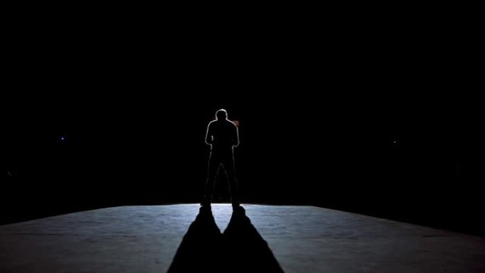 穿着服装的高级男子在黑暗中的舞台上。剧院表演期间，活跃的帽子男子在舞台上跳舞。