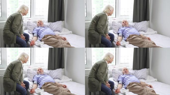 一位老年妇女照顾男人，用眼压计帮助测量血压。一名男子躺在高血压床上
