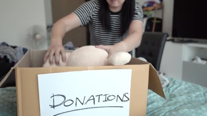 亚洲妇女在捐赠箱中打包衣服。