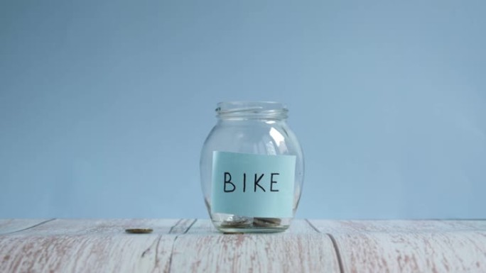 为自行车省钱。将硬币扔进带有铭文自行车的玻璃罐中。省钱概念