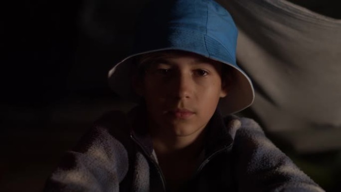 戴着蓝色帽子的严重欺负男孩坐在室内看着相机