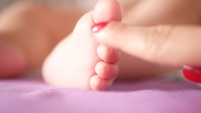 妈妈抚摸着新生婴儿的脚。妈妈抱着婴儿脚的特写镜头。母亲抚摸着刚出生的婴儿的手指。母亲轻轻地抚摸着刚出