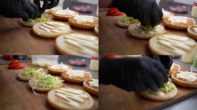 汉堡由面包，肉排，蔬菜和酱汁制成。儿童节日菜单。厨师手的特写镜头。