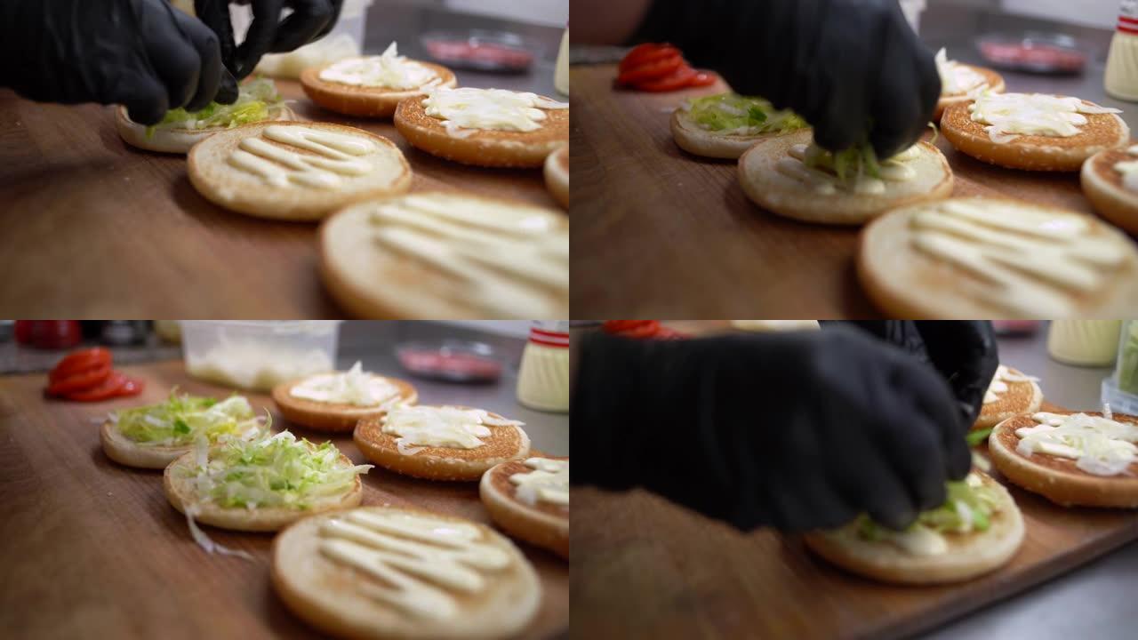 汉堡由面包，肉排，蔬菜和酱汁制成。儿童节日菜单。厨师手的特写镜头。