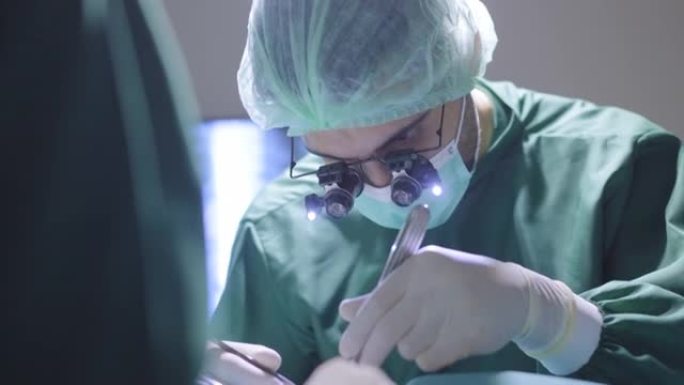 在压力下共同努力挽救亚洲女性患者躺在医院手术室床上的生命，以挽救生命。佩戴双目放大镜的外科医生的特写