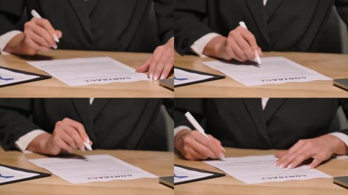 女商人用钢笔合同检查和签字。穿着黑色西装的女人坐在办公室的桌子旁。签署工作文件、协议或交易。特写。慢