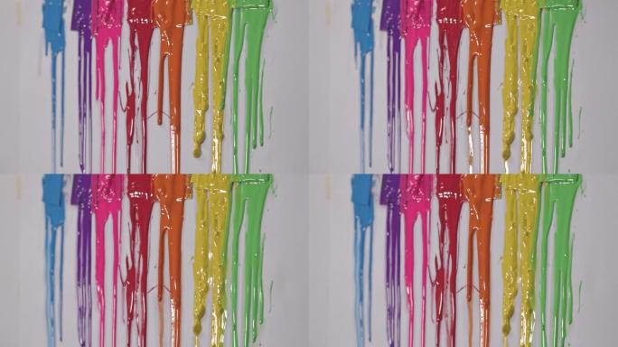 彩虹颜料正在慢慢从彩色勺柄上滴下来。