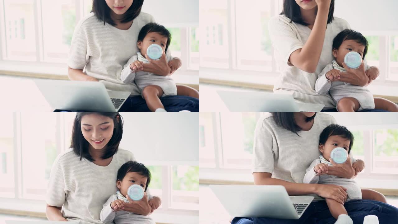 母亲在笔记本电脑上工作时在家给婴儿奶瓶
