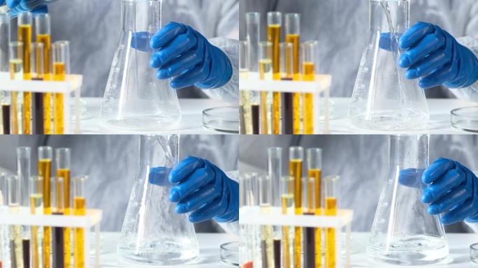 现代实验室的防护服和手套化学家将透明溶液倒入大型玻璃管中。实验室研究和制药技术。药理学工业中的生物学