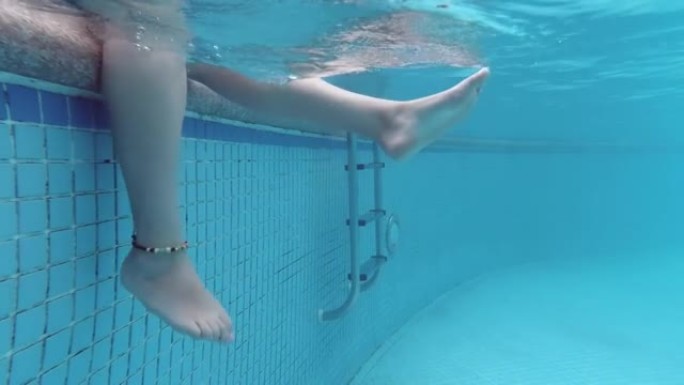 温柔女人用脚泼水的水下视图。炎热夏日的快乐。游泳池和阳光。