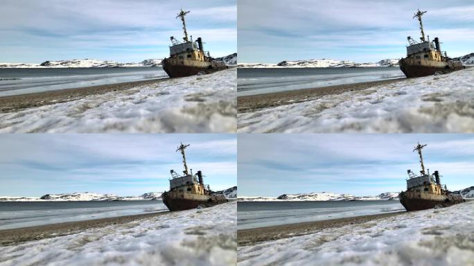 在下雪的冬季，在海边淹死的旧失事渔船的空中俯视图。镜头。俄罗斯特里伯卡雪沙海岸附近冷水中被毁船的鸟瞰
