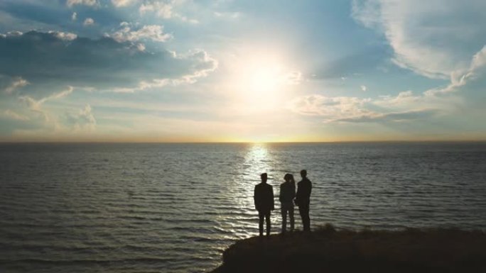 三个人站在山顶上，靠着美丽的海景