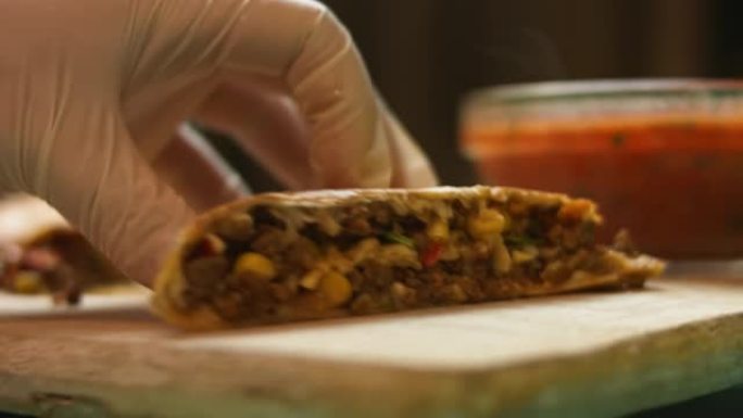 在木制切菜板上切新鲜油炸的热牛肉饼。制作墨西哥玉米饼的过程。侧视图