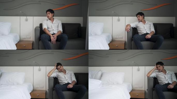 患有抑郁症的亚洲男子坐在卧室的沙发上。
