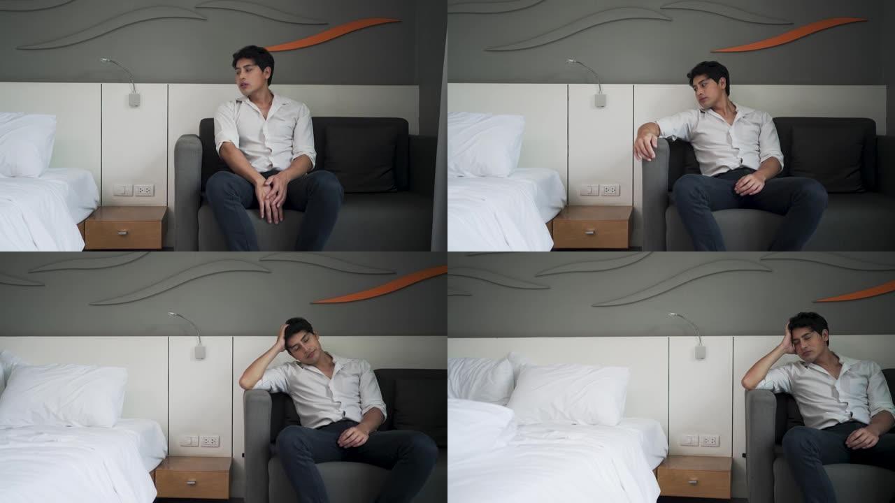患有抑郁症的亚洲男子坐在卧室的沙发上。
