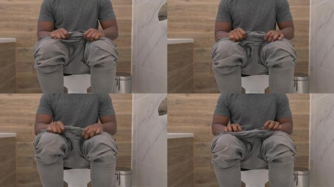 穿着裤子的男人坐在厕所里，穿着裤子在浴室里。消化问题。便秘或腹泻。医疗保健概念