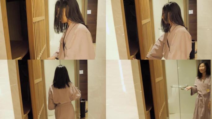 快乐的亚洲女孩穿着灰色浴袍，走出酒店的浴室，生活理念。