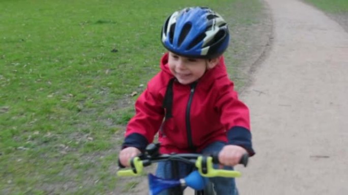 可爱的孩子，蹒跚学步的男孩，在公园骑自行车，春天