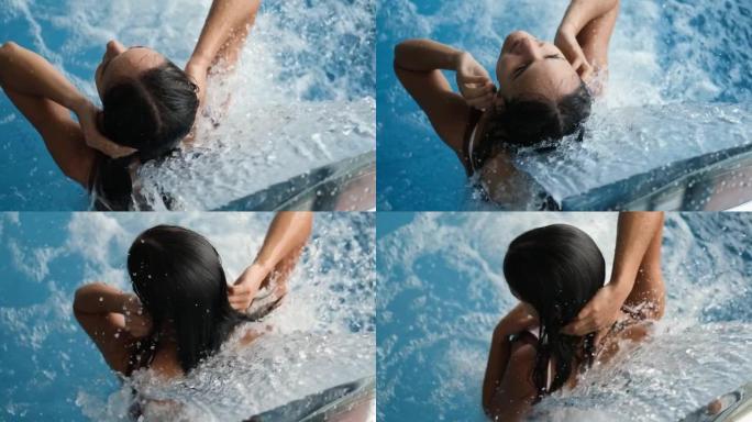 特写的年轻女子在水疗酒店的游泳池里接受水疗。美丽的女孩用水力按摩放松