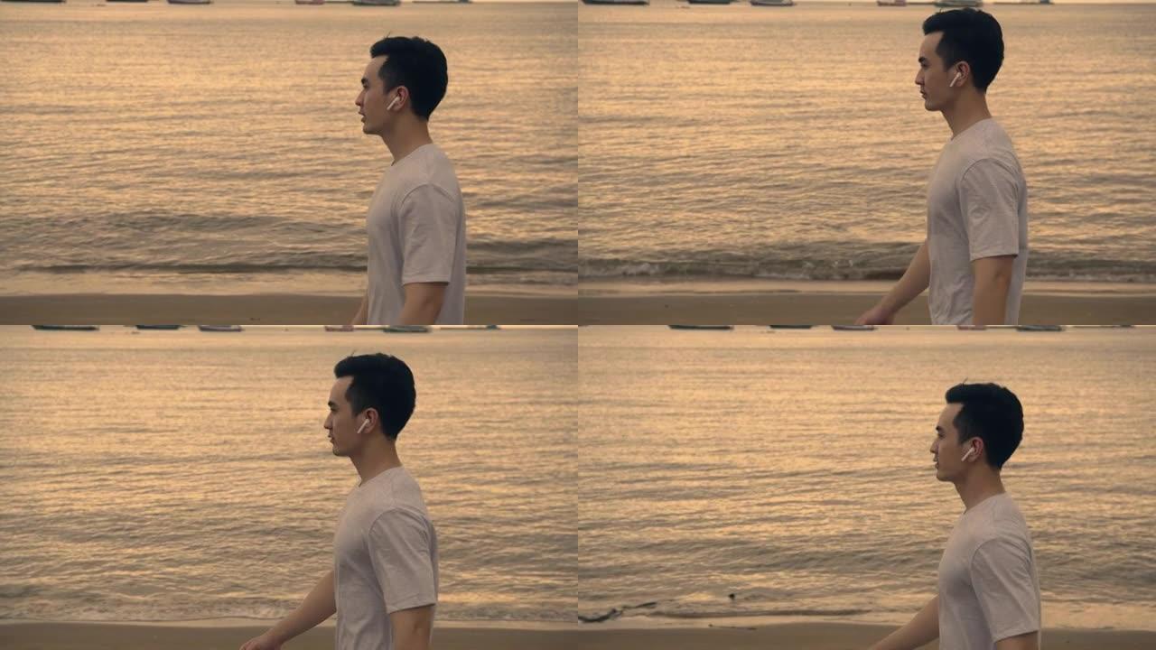 迷人的亚洲男子跑步者在夏天美丽的日落时在海滩上散步。户外锻炼训练概念。