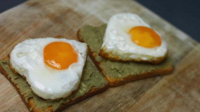 在烤面包上的心形鸡蛋，在木板上捣碎鳄梨。为3月8日做惊喜早餐。艺术拍摄
