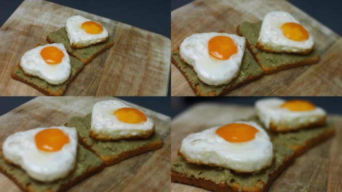 在烤面包上的心形鸡蛋，在木板上捣碎鳄梨。为3月8日做惊喜早餐。艺术拍摄