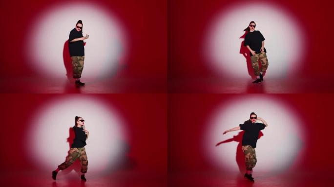 跳舞的年轻嘻哈女孩在红光下的聚光灯下表演自由式舞蹈。现代生活方式，霹雳舞和说唱