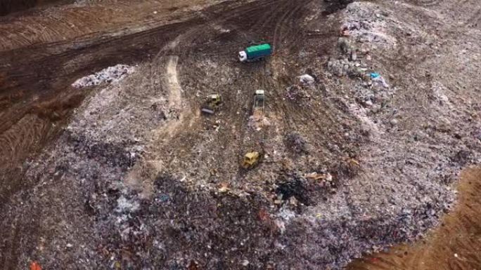 在垃圾填埋场工作的推土机的鸟瞰图。环境污染。垃圾填埋场。垃圾车在垃圾填埋场卸载家庭垃圾
