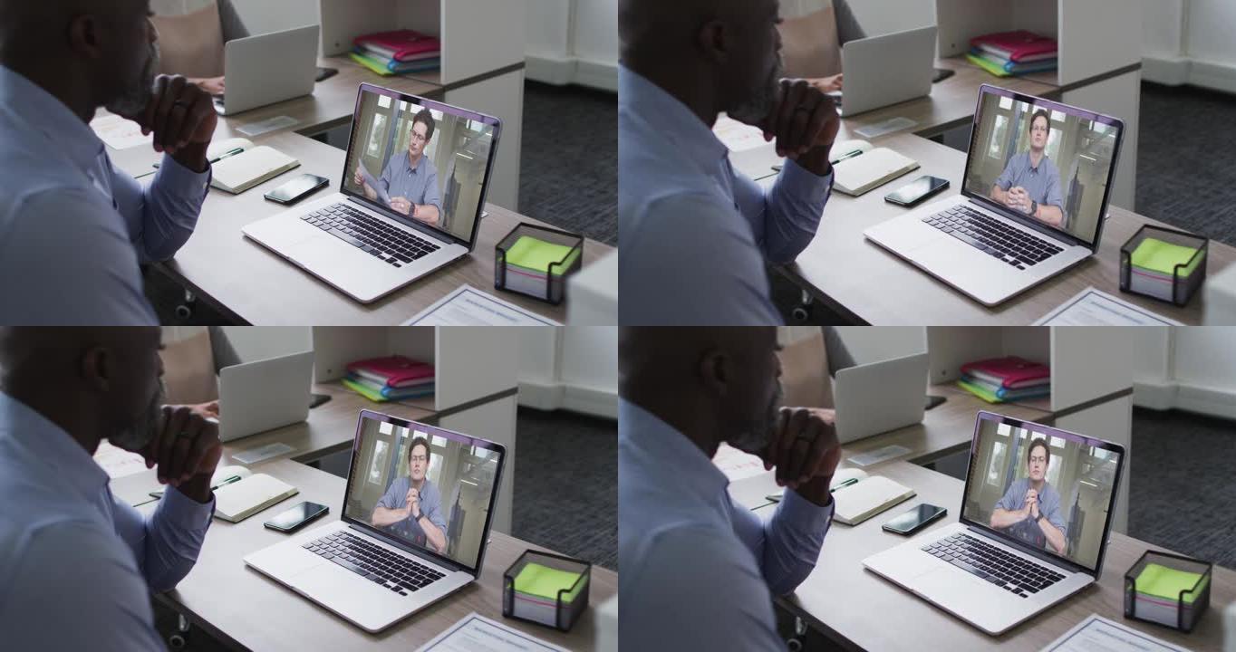 非裔美国高级男子在笔记本电脑上与办公室的男性同事进行视频通话