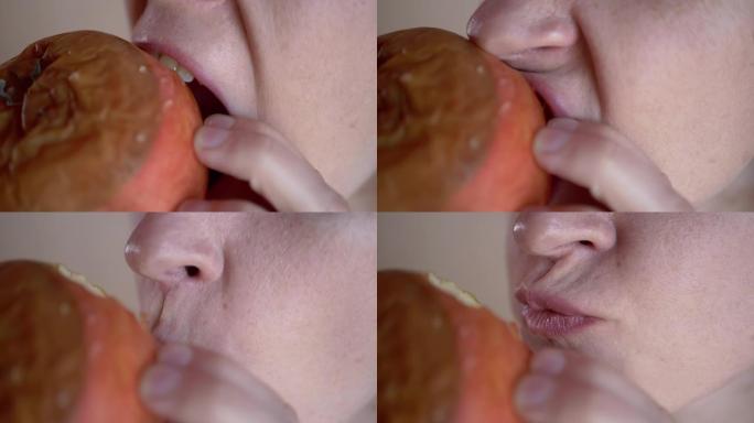 女人用牙齿咬掉一块烂苹果。变质发霉的水果