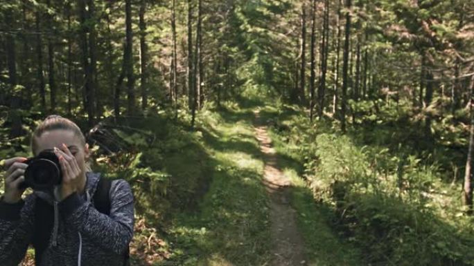 旅行者在森林中拍摄风景。一个白人女人射出漂亮的魔法。女孩在dslr无反光镜相机上拍摄照片视频。